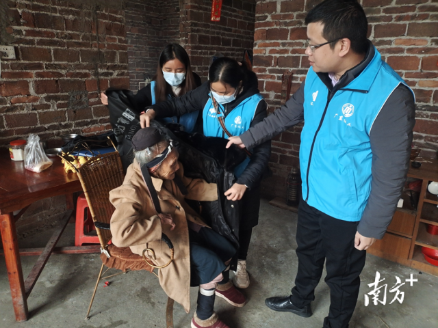 連南瑤族自治縣香坪鎮(zhèn)社工站為困難高齡老人送去御寒棉衣，并幫老人穿上棉衣。